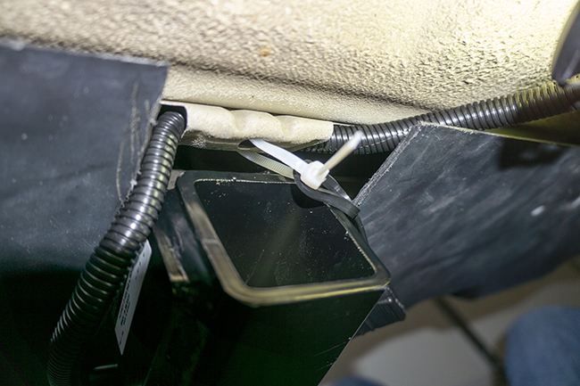 Photograph of Hopkins plug in vehicle wiring harness with 4 pole connector attached to a Draw Tite Max Frame receiver hitch on a 2010 Subauru Outback, showing how to zip tie the wiring to the car's center rear body tab.